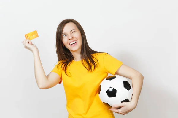 Bella europea giovane donna allegra, tifoso di calcio o giocatore in uniforme gialla in possesso di carta di credito palla da calcio isolato su sfondo bianco. Sport, gioco di calcio, concetto di stile di vita eccitante . — Foto Stock