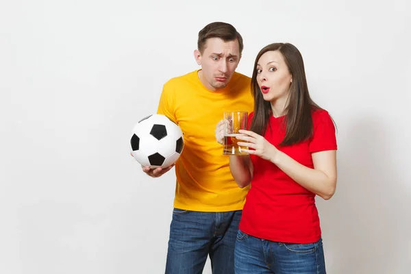 Fun jeune couple fou, femme, homme, fans de football en uniforme jaune rouge remonter le moral équipe de soutien avec tasse de bière pinte, ballon de football isolé sur fond blanc. Sport, loisirs en famille, concept lifestyle . — Photo
