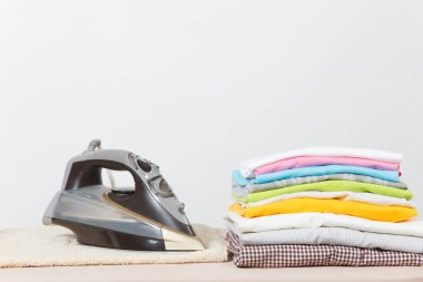 Buharlı Ütü, Çamaşırhane, yıkanmış renkli elbise Ütü kadar yakın aile giyim üzerine Ütü Masası beyaz arka plan üzerinde izole. Temizlik kavramı. Reklam için yer kopyalayın. Metin için yer.