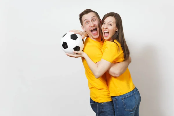 Diversión loca alegre joven pareja emocional, mujer, hombre, aficionados al fútbol en uniforme amarillo animar equipo de apoyo con pelota de fútbol aislado sobre fondo blanco. Deportes, ocio familiar, concepto de estilo de vida . —  Fotos de Stock