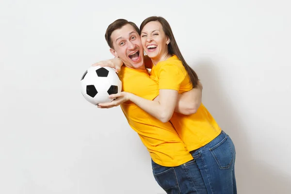 Весела весела емоційна молода пара, жінка, чоловік, шанувальники футболу в жовтій формі підбадьорюють команду підтримки з футбольним м'ячем ізольовано на білому тлі. Спорт, сімейне дозвілля, концепція способу життя . — стокове фото
