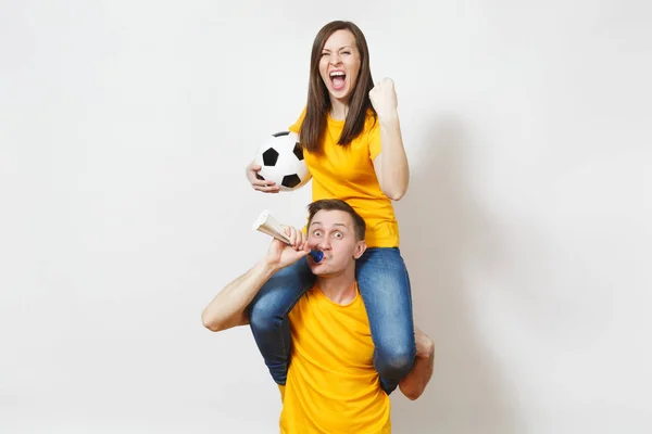 Jeune couple inspiré, femme assise sur les épaules de l'homme, fans avec ballon de football pipe acclamer équipe de football préférée mains gesticulées expressives isolées sur fond blanc. Loisirs en famille, concept lifestyle . — Photo