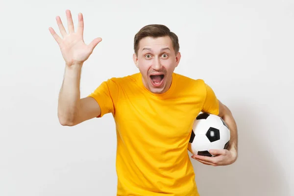 Ispirato giovane uomo europeo, tifoso o giocatore in uniforme gialla tenere palla da calcio, tifo squadra di calcio preferita, espressivo gesticolare mani isolate su sfondo bianco. Il concetto di stile di vita. Copia spazio . — Foto Stock