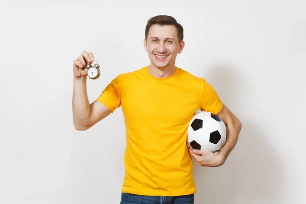 Ispirato giovane allegro uomo europeo, fan o giocatore in uniforme gialla tenere palla da calcio, vecchia sveglia, tifo squadra preferita isolata su sfondo bianco. Sport, calcio, lifestyle concept . — Foto Stock