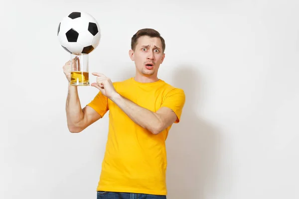 Triste sconvolto giovane uomo europeo disorientato, tifoso o giocatore in uniforme gialla tenere pinta tazza di birra, squadra di calcio preferito tifo palla isolato su sfondo bianco. Sport, gioco, lifestyle concept . — Foto Stock