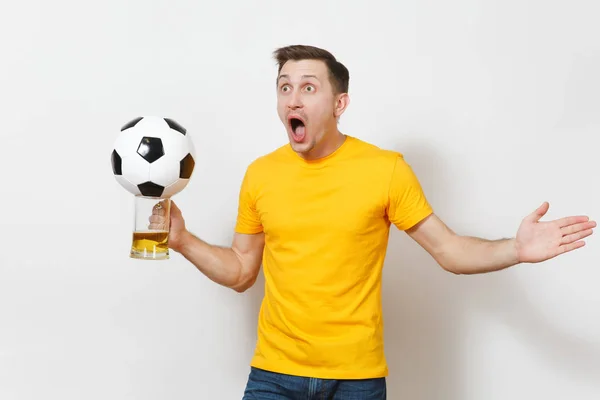 Ispirato giovane divertente allegro uomo europeo, fan o giocatore in uniforme gialla tenere pinta tazza di birra, pallone da calcio tifo squadra di calcio preferita isolata su sfondo bianco. Sport, gioco, lifestyle concept . — Foto Stock