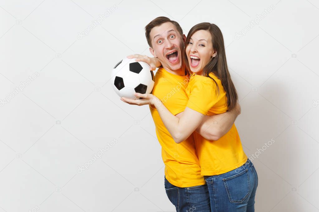 Fun crazy cheerful emotional young couple, woman, man, football fans in yellow uniform cheer up support team with soccer ball isolated on white background. Sport, family leisure, lifestyle concept.