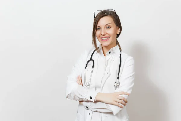 Sonriente mujer doctora joven y segura de sí misma con estetoscopio, gafas aisladas sobre fondo blanco. La doctora en bata médica tiene las manos cruzadas. Personal sanitario, salud, concepto de medicina . — Foto de Stock
