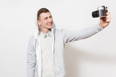 Genç t-shirt ve kukuleta ile kulaklık fotoğraf ile hafif kazak erkek öğrenci kendini retro kameraya gülümseyen yakışıklı beyaz arka plan üzerinde izole. Genel kavram-in fotoğraf, hobi
