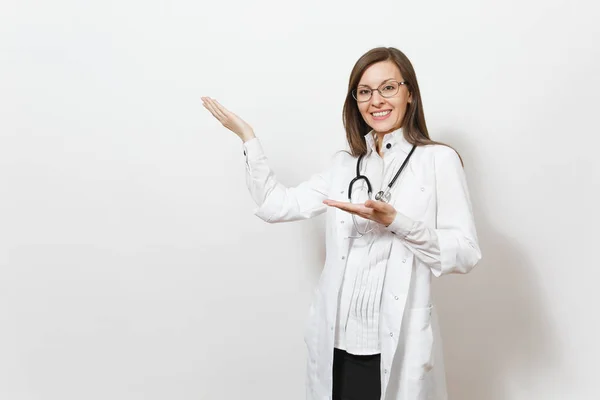 Mujer joven y sonriente con estetoscopio, gafas aisladas sobre fondo blanco. Doctora en bata médica señalando con la mano a un lado en el espacio de copia. Personal sanitario, salud, concepto de medicina . — Foto de Stock