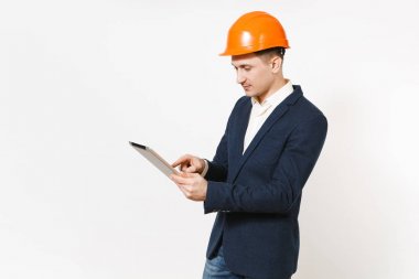 Koyu takım elbise, beyaz arka plan üzerinde izole tablet pc bilgisayar kullanarak koruyucu inşaat turuncu kask genç yakışıklı başarılı işadamı. Erkek işçi reklam için. İş kavramı.