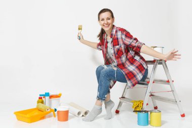 Rahat kıyafetler merdiven fırça ile beyaz arka plan üzerinde izole yenileme daire için aygıtlar üzerinde oturan güzel kadın. Duvar kağıdı, yapıştırma, boyama araçları için aksesuarlar. Onarım ev concept.