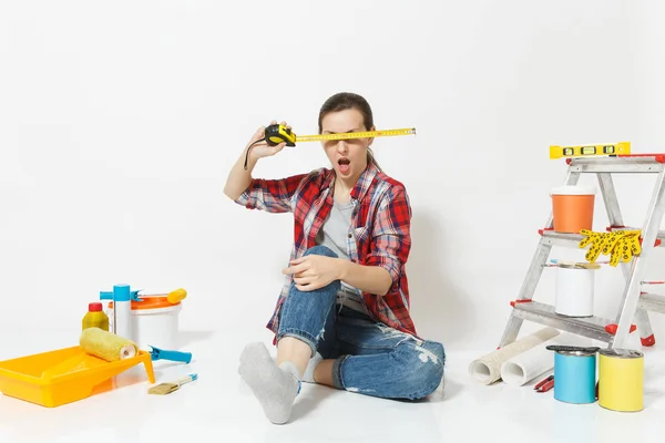 Mulher em roupas casuais sentado no chão com fita métrica, instrumentos para renovação apartamento isolado em fundo branco. Papel de parede, acessórios para colar, ferramentas de pintura. Reparação home concept . — Fotografia de Stock