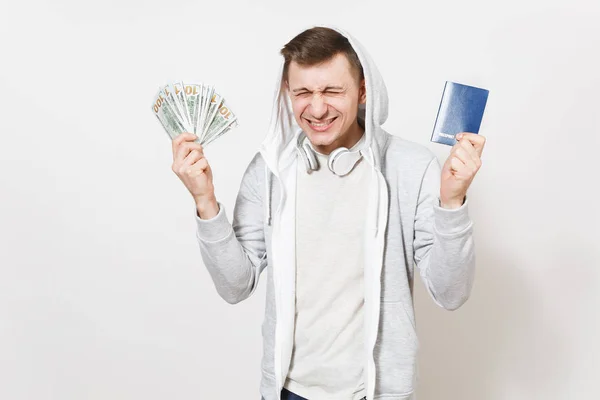 Fiatal férfi izgatott férfi póló, könnyű pulóver kapucnis fejhallgatóval rendelkezik nemzetközi útlevél, bundle dollárt, elszigetelt fehér background készpénzre. Utazás, turizmus fogalmának. — Stock Fotó