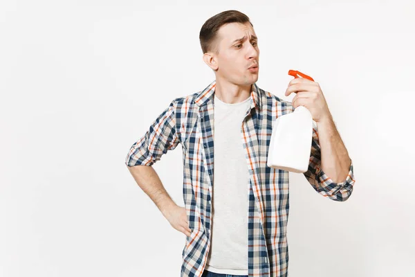 Jonge huishoudster man in geruit overhemd blazen op witte lege lege schoonmaak spray fles met schonere vloeistof geïsoleerd op een witte achtergrond. Man huis klusjes doen. Ruimte voor reclame kopiëren. — Stockfoto