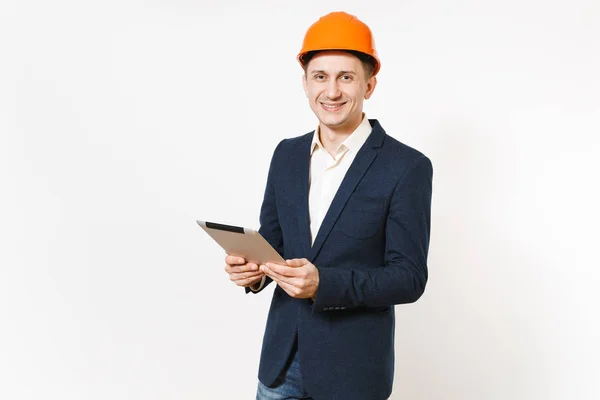 Jovem bonito sorridente empresário em terno escuro, capacete de construção protetora segurando tablet pc computador isolado no fundo branco. Trabalhador masculino para propaganda. Negócio, conceito de trabalho . — Fotografia de Stock