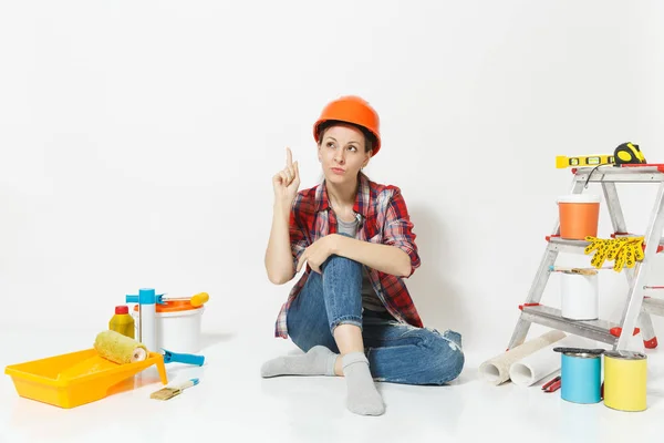 Mulher pensativa em capacete de proteção laranja sentado no chão com instrumentos para renovação apartamento isolado no fundo branco. Papel de parede, acessórios para colar ferramentas de pintura. Reparação home concept — Fotografia de Stock