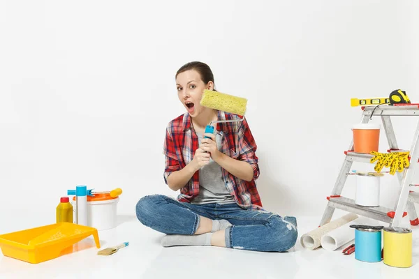Γυναίκα σε casual ρούχα που κάθεται στο πάτωμα με κυλινδρικό χρωστήρα, όργανα για διαμέρισμα ανακαίνιση που απομονώνονται σε λευκό φόντο. Ταπετσαρία, αξεσουάρ για την κόλληση, εργαλεία ζωγραφικής. Επισκευή concept home. — Φωτογραφία Αρχείου