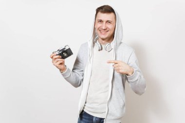 Genç yakışıklı gülümseyen adam öğrenci tişört ve kulaklık ile hood ile hafif kazak retro kamera tutan ve kendisine beyaz arka plan üzerinde izole parmak ile işaret. Genel kavram-in fotoğraf, hobi