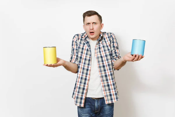 Jovem homem chocado em roupas casuais segurando latas de lata de tinta vazias com espaço de cópia isolado no fundo branco. Instrumentos, acessórios, ferramentas para renovação apartamento quarto. Reparação home concept . — Fotografia de Stock