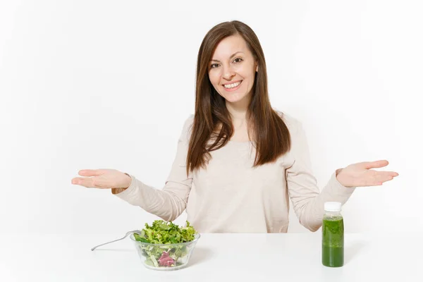 Woman spread hands at table with green detox smoothies, salad in glass bowl isolated on white background. Proper nutrition, vegetarian food, healthy lifestyle, dieting concept. Area with copy space. — Stock Photo, Image