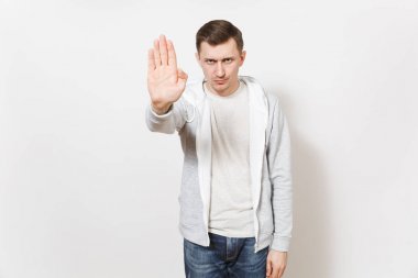 T-shirt, kot ve ışık kazak dur hareketi ile palm, gösterilen genç ciddi ciddi adam frowns izole üzerinde beyaz arka plan. Duygular, iyi bir ruh hali kavramı. Kopya alanı reklam için.