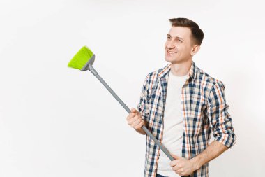 Genç gülümseyen mutlu ev kadını adam tutarak ve beyaz arka plan üzerinde izole yeşil süpürge ile süpürme gömlek damalı. Erkek ev ev işleri yaparak. Reklam için yer kopyalayın. Temizlik kavramı.
