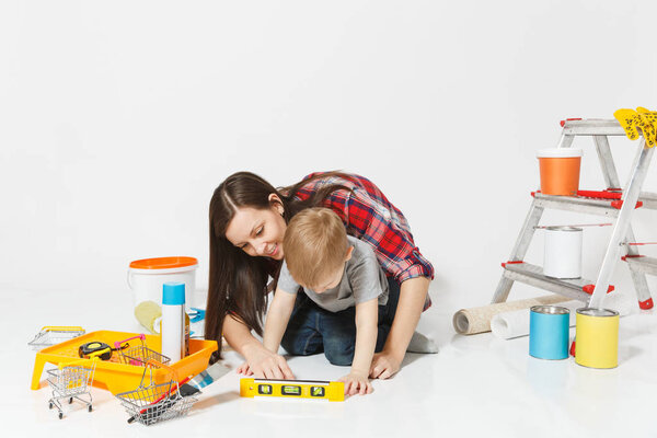 Mother and small son with instruments for renovation apartment room isolated on white background. Wallpaper, gluing accessories, painting tools. Boy woman repairing home. Parenthood childhood concept.