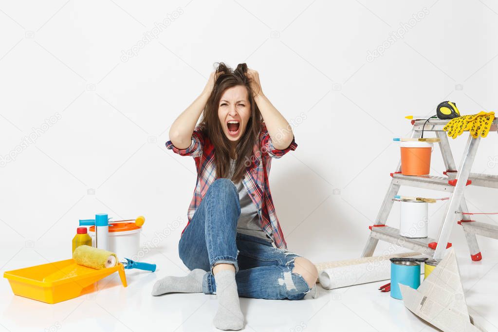 Confused screaming mad shocked woman sitting on floor with instruments for renovation apartment isolated on white background. Wallpaper, accessories for gluing, painting tools. Concept of repair home.
