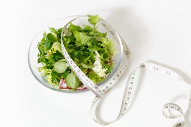 Yeşil sebzeler salata cam kase kadar yakın, beyaz arka plan üzerinde izole ölçüm bandı terzi. Doğru beslenme, Vejetaryen Gıda, sağlıklı yaşam, diyet yemek. Diyabet diyet kavramı. Kopya alanı