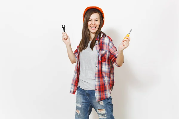 Joven mujer muy alegre en la construcción protectora casco naranja celebración destornillador de juguete y llave aislada sobre fondo blanco. Instrumentos, herramientas para la renovación de la habitación del apartamento. Reparación concepto hogar . —  Fotos de Stock