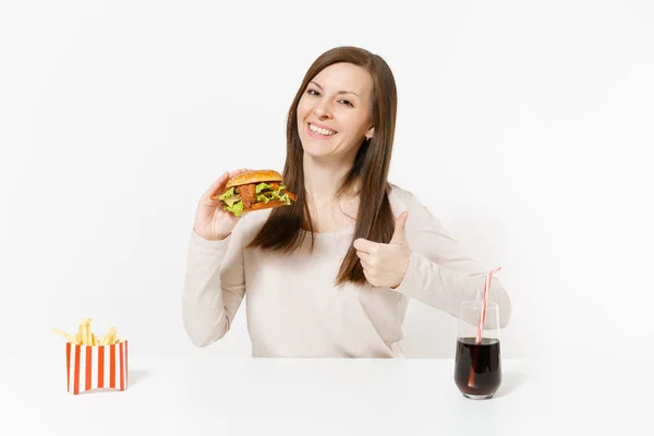 Mulher bonita sentada à mesa com hambúrguer, batatas fritas, cola em garrafa de vidro isolado no fundo branco. Nutrição adequada ou fast food clássico americano. Área de publicidade com espaço de cópia . — Fotografia de Stock