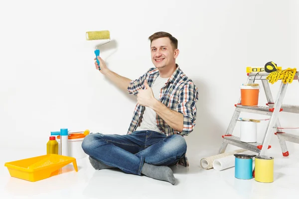 Ο άνθρωπος που κάθεται στο πάτωμα χρησιμοποιώντας σχετικά με τοίχο κυλινδρικό χρωστήρα, όργανα για ανακαίνιση Διαμέρισμα Δωμάτιο απομονωθεί σε λευκό φόντο. Ταπετσαρία, κόλλημα αξεσουάρ, εργαλεία βαφής. Επισκευή concept home. Χώρο αντίγραφο. — Φωτογραφία Αρχείου