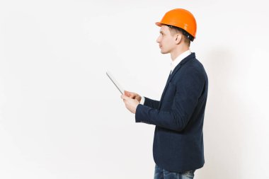 Genç yakışıklı işadamı koyu takım, tablet pc bilgisayar basılı tutup kenara beyaz arka plan üzerinde izole kopya alanı üzerinde seyir koruyucu kask. Erkek işçi reklam için. İş kavramı.