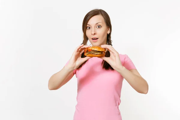 Genç güzel kadın pembe t-shirt holding örgüler ile beyaz arka plan üzerinde izole burger eller. Doğru beslenme veya Amerikan Klasik fast food. Reklam için yer kopyalayın. Reklam alanı. — Stok fotoğraf