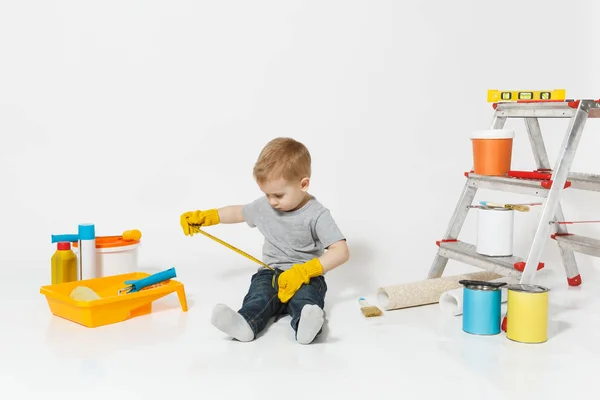 Маленький симпатичный мальчик в желтых перчатках с инструментами для ремонта квартиры изолирован на белом фоне. Обои, клеящие аксессуары, инструменты для покраски. Ремонт дома. Родительство, концепция детства . — стоковое фото