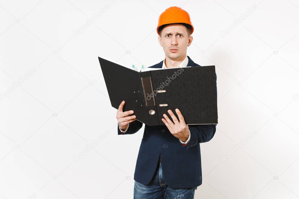 Exhausted dissatisfied businessman in dark suit, protective construction helmet holding black folder for papers document isolated on white background. Male worker for advertisement. Business concept.