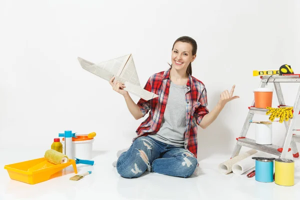 Donna in abiti casual seduta al piano con cappello di giornale, strumenti per la ristrutturazione appartamento isolato su sfondo bianco. Carta da parati, accessori per l'incollaggio, strumenti di pittura. Riparazione concetto di casa . — Foto Stock