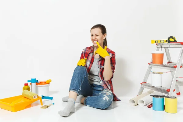 Spaß hübsche Frau in lässiger Kleidung sitzt auf dem Boden mit gelben Handschuhen, Instrumente für die Renovierung Wohnung isoliert auf weißem Hintergrund. Tapeten-Zubehör für Malwerkzeuge. Heimkonzept reparieren — Stockfoto