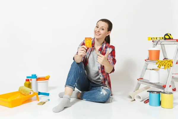 Χαριτωμένο γυναίκα κρατώντας πιστωτική κάρτα με τα χρήματα που κάθεται στο πάτωμα με τα όργανα για διαμέρισμα ανακαίνιση που απομονώνονται σε λευκό φόντο. Ταπετσαρία αξεσουάρ για την κόλληση εργαλεία ζωγραφικής. Επισκευή concept home. — Φωτογραφία Αρχείου