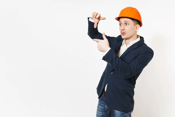 Jovem bonito empresário bem sucedido em terno escuro, capacete de construção protetora fazendo mãos foto frame gesto isolado no fundo branco. Trabalhador masculino para propaganda. Conceito de negócio . — Fotografia de Stock