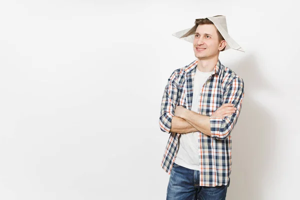 Jovem sorrindo homem bonito em roupas casuais e chapéu de jornal de mãos dadas dobrado isolado no fundo branco. Acessórios para renovação apartamento quarto. Conceito de casa de reparação. Área publicitária . — Fotografia de Stock