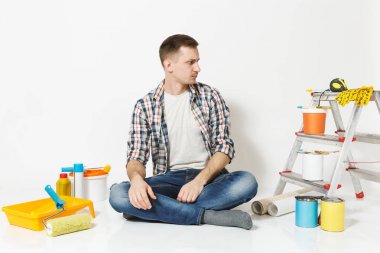 Beyaz arka plan üzerinde izole yenileme daire oda için aygıtlar ile katta oturan rahat kıyafetler ciddi dalgın adam. , Duvar kağıdı yapıştırma aksesuarları, boyama araçlarını. Onarım ev concept.
