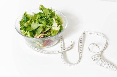 Yeşil sebzeler salata cam kase kadar yakın, beyaz arka plan üzerinde izole ölçüm bandı terzi. Doğru beslenme, Vejetaryen Gıda, sağlıklı yaşam, diyet yemek. Diyabet diyet kavramı. Kopya alanı
