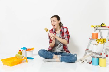 Eğlenceli fırça, yenileme daire oda için aygıtlar ile katta oturan rahat kıyafetler kadında beyaz arka plan üzerinde izole. Duvar kağıdı, yapıştırma, boyama araçları için aksesuarlar. Onarım ev concept.