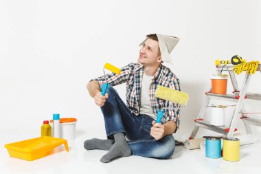 Boya merdaneleri, yenileme daire oda için aygıtlar ile katta oturan gazete şapkalı adam beyaz arka plan üzerinde izole. , Duvar kağıdı yapıştırma aksesuarları, boyama araçlarını. Onarım ev concept.