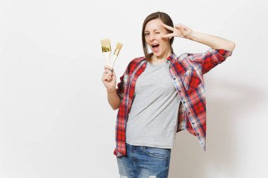 Genç güzel kadın rahat kıyafetler holding Boya fırçaları ve beyaz arka plan üzerinde izole gösteren zafer işareti eğlenceli. Aletleri, yenileme daire oda için aksesuarlar. Onarım ev concept.