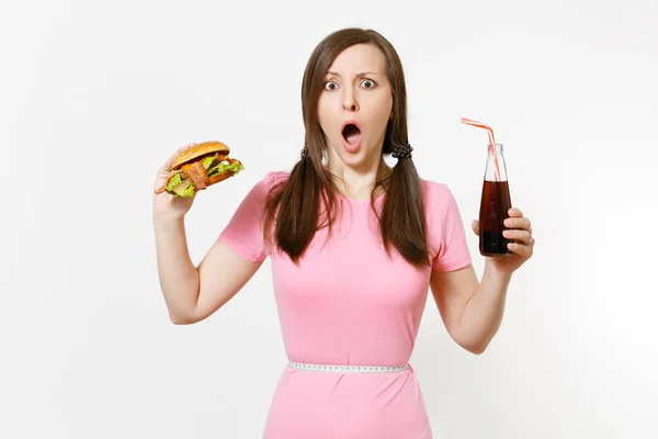 Leuke jonge vrouw met staarten, meetlint bij taille hamburger, in glazen fles cola te houden geïsoleerd op een witte achtergrond. Goede voeding of Amerikaanse klassieke fastfood. Gebied met kopie ruimte reclame. — Stockfoto