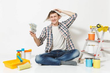 Mutlu adam gazete şapkalı bohça-in dolar, nakit para tutar. Beyaz arka plan üzerinde izole yenileme daire için aygıtlar. , Duvar kağıdı yapıştırma aksesuarları, boyama araçlarını. Onarım ev concept.