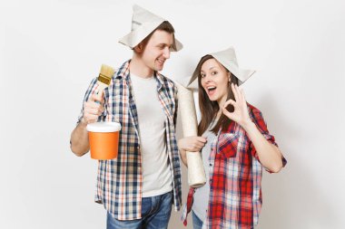 Genç mutlu kadın, adam rahat kıyafetler boya fırçası, holding boya kovası ve duvar kağıdı rulo. Beyaz arka plan üzerinde izole çift. Yenileme daire oda için aygıtlar. Onarım ev concept.